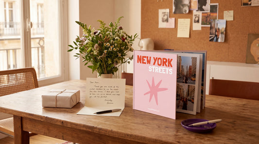 Mesa con varias ideas de regalo para una amiga, incluyendo un fotolibro personalizado y una tarjeta escrita a mano.
